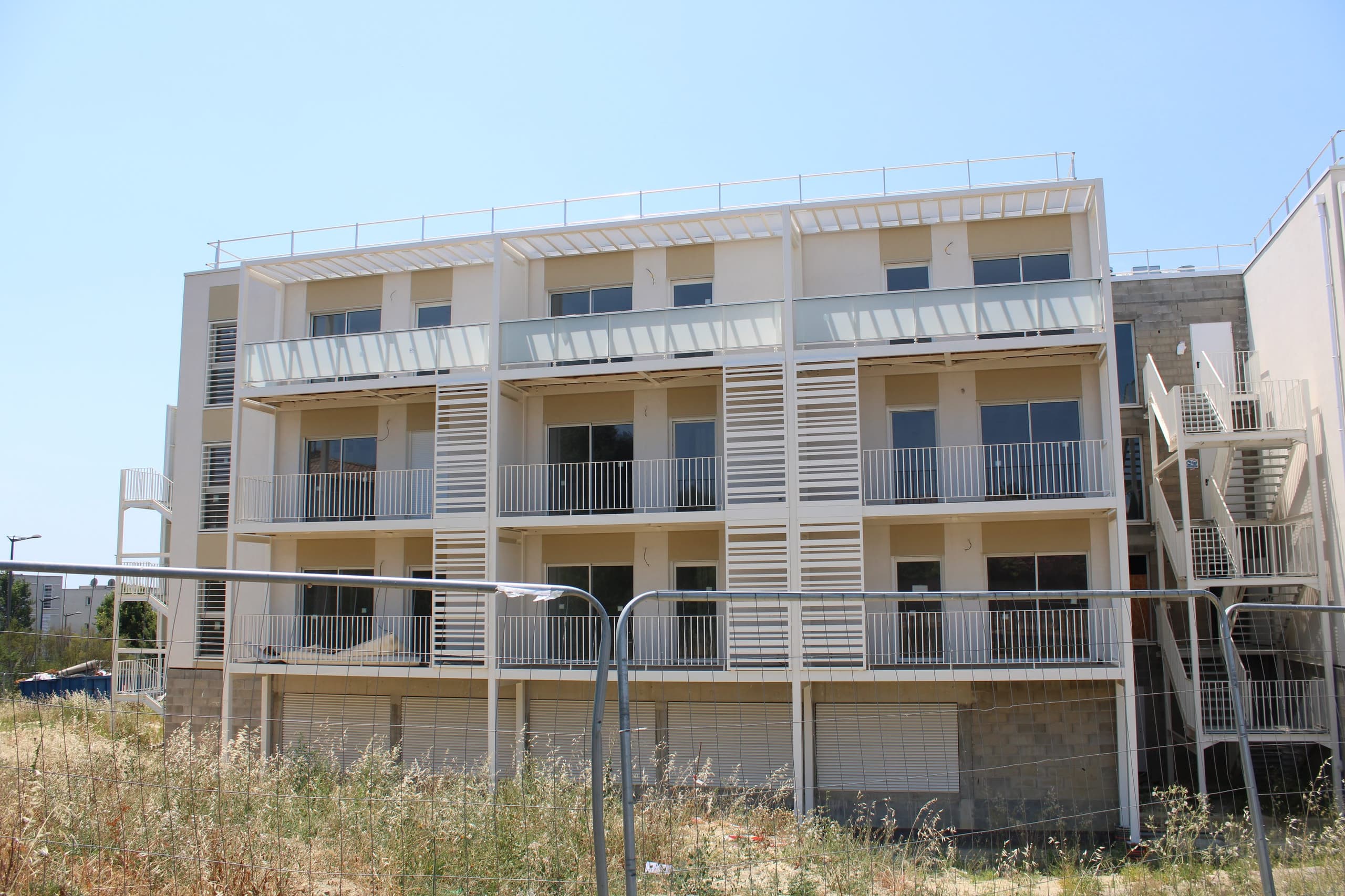 La Résidence Vestia à Béziers : quatre niveaux, garde-corps et brise-soleil blancs, escalier extérieur