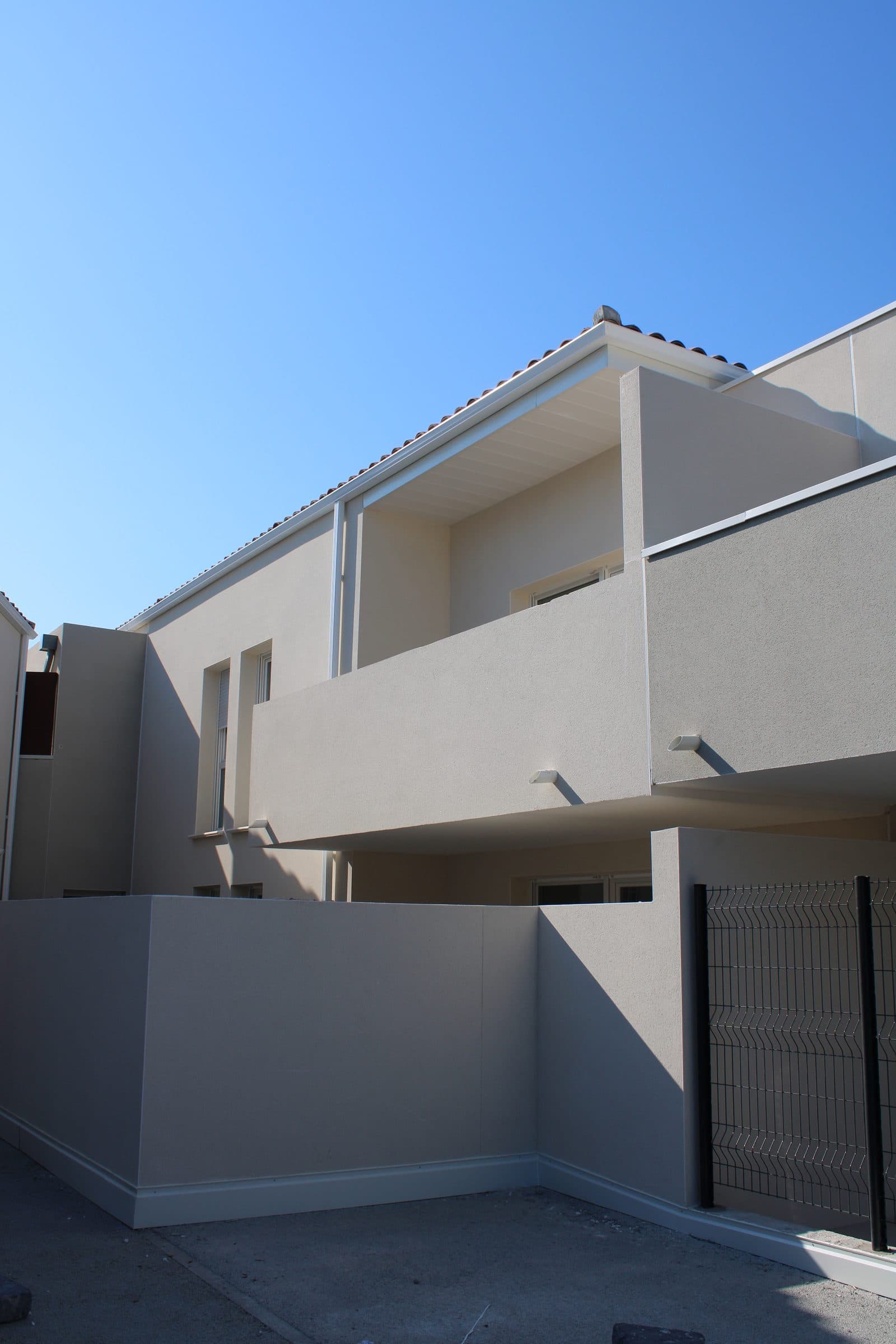 Un balcon et une terrasse en angle, façades enduites gris clair