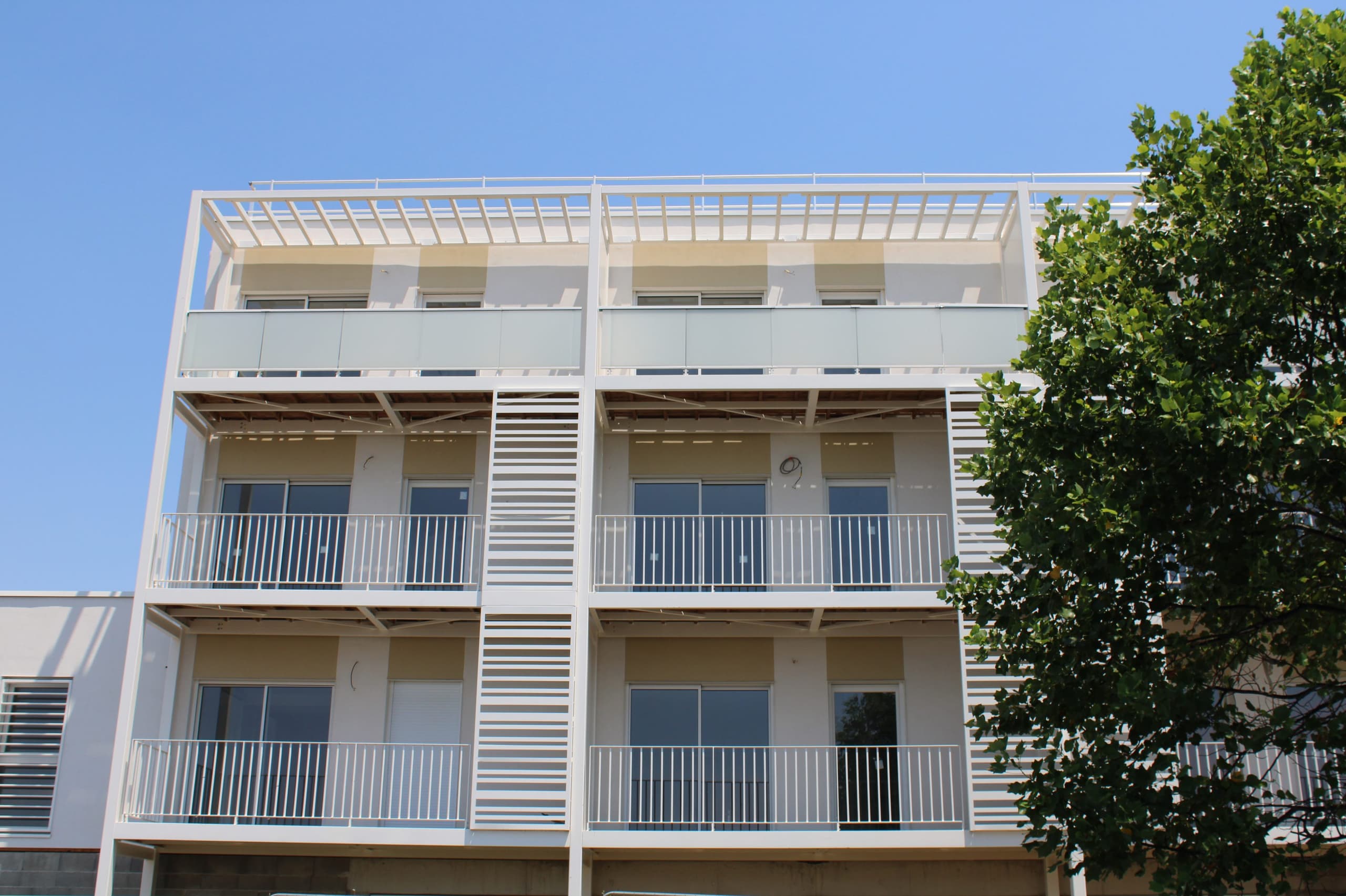 Façade de la résidence : balcons filants, garde-corps et brise-soleil blancs