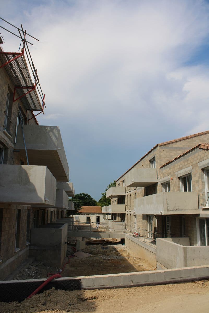 Une allée de chantier entre deux ailes de la résidence, balcons en béton brut