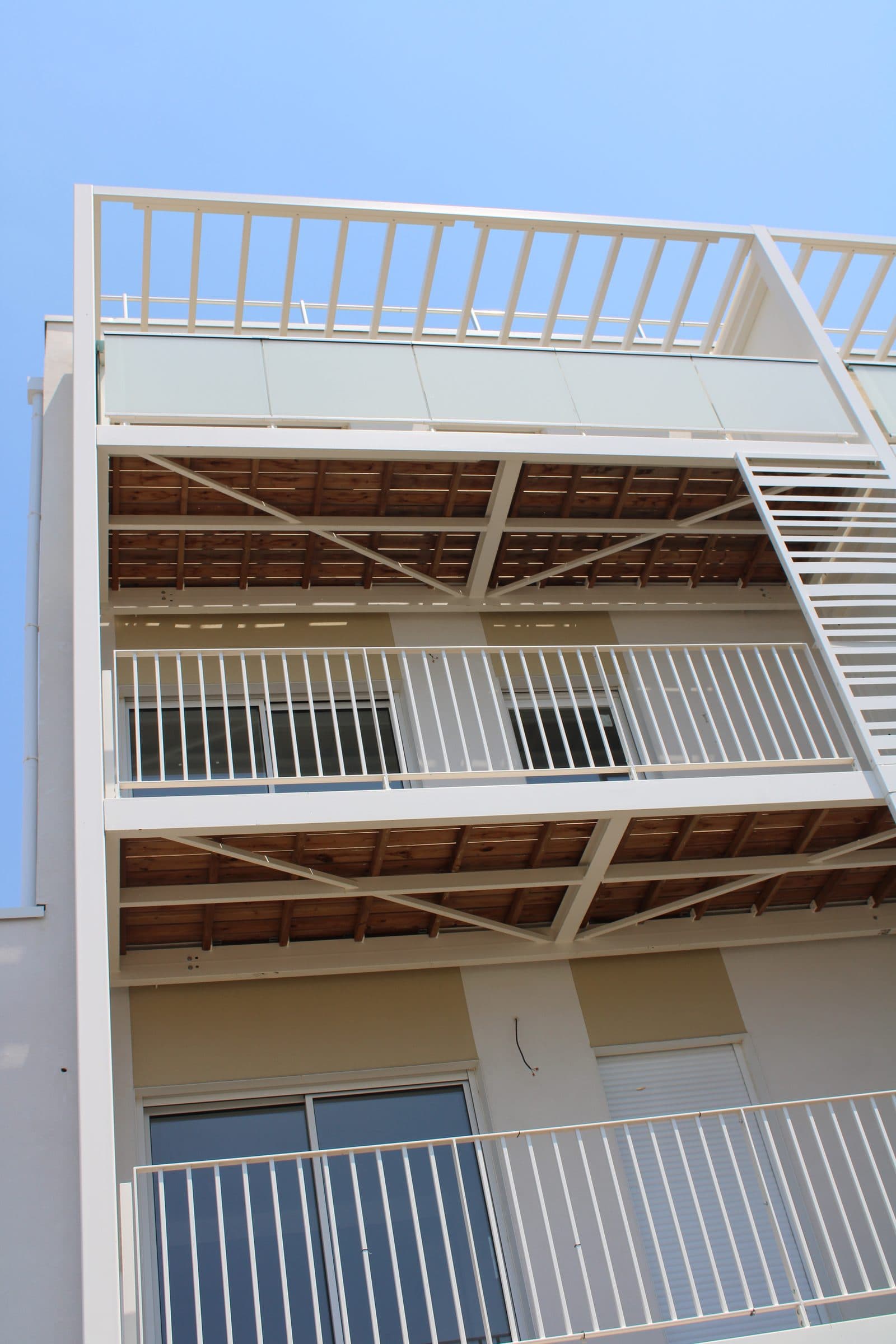 Sous-faces en bois et garde-corps blancs des balcons, en contre-plongée