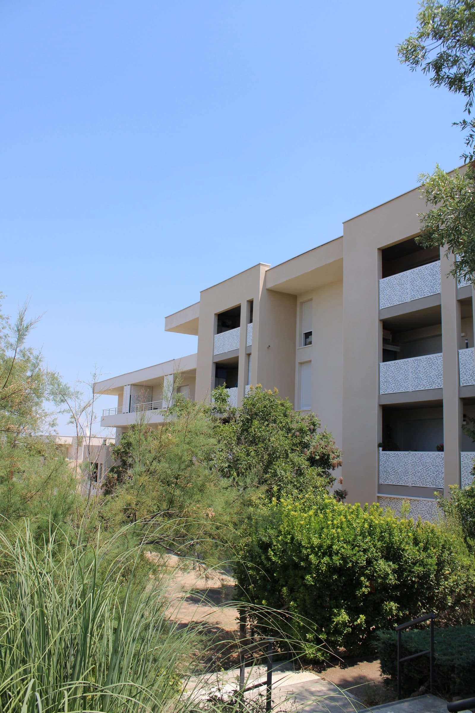 Un bâtiment de la résidence vu depuis le jardin, entre graminées et arbustes