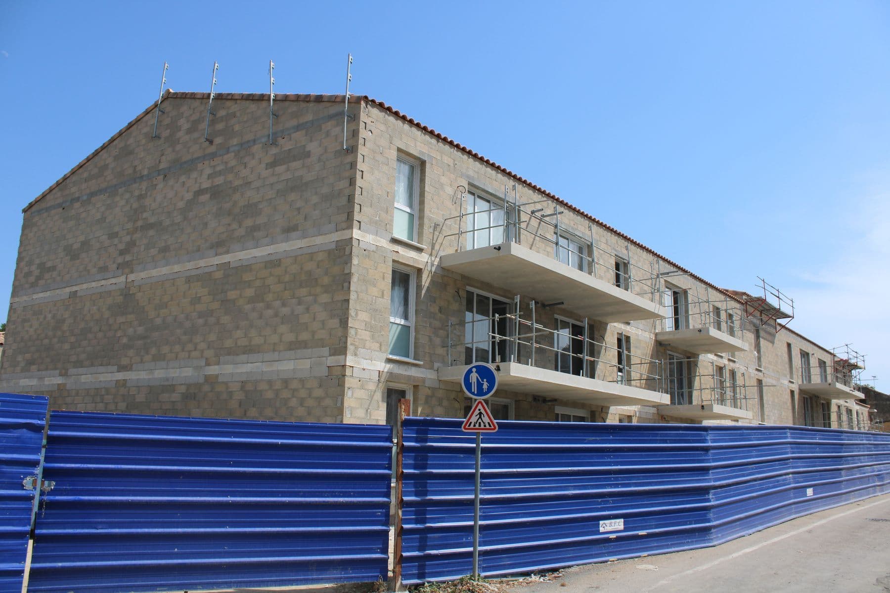La résidence derrière la palissade bleue du chantier, le long de la rue