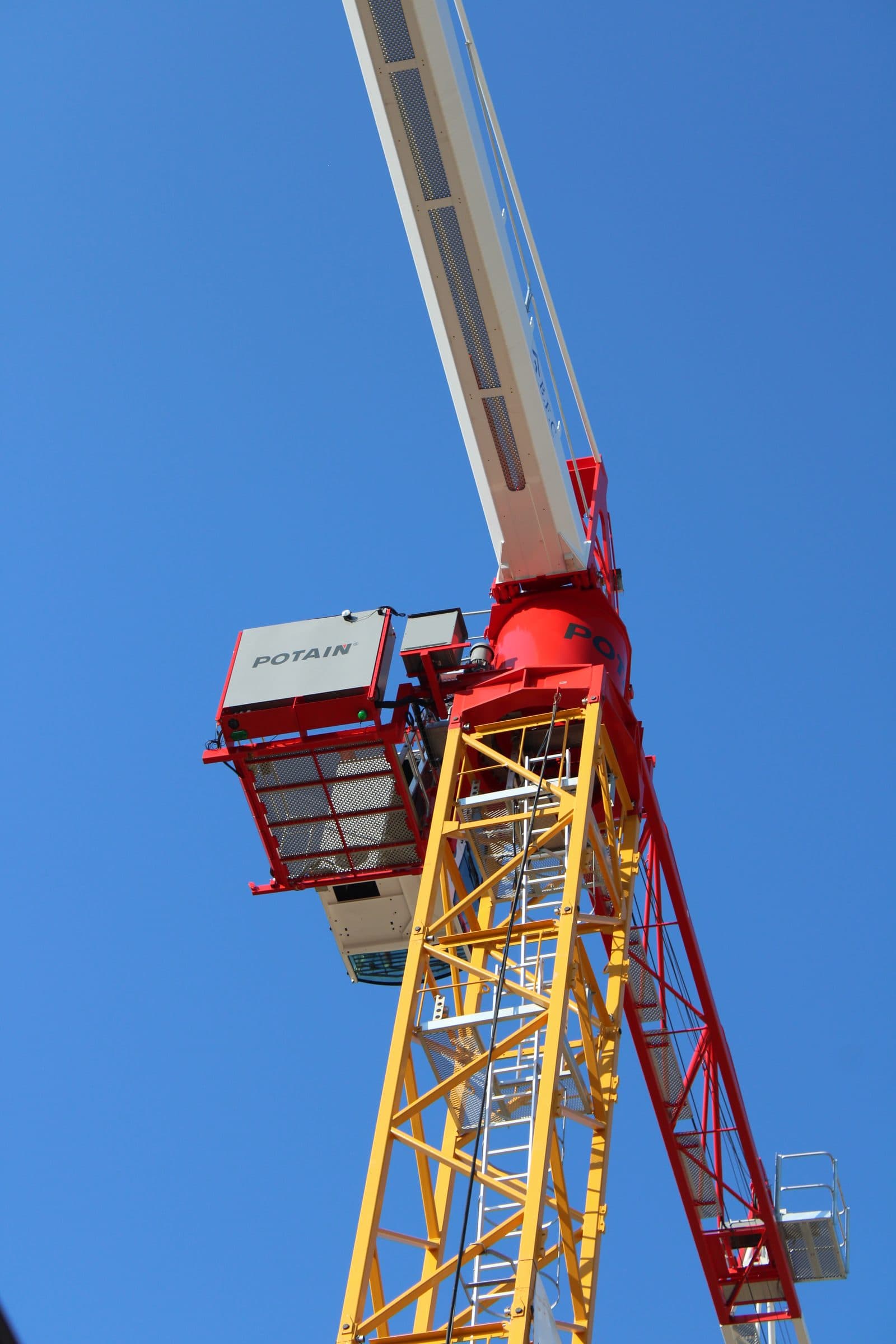 La cabine et la flèche d’une grue à tour, en contre-plongée sur le ciel