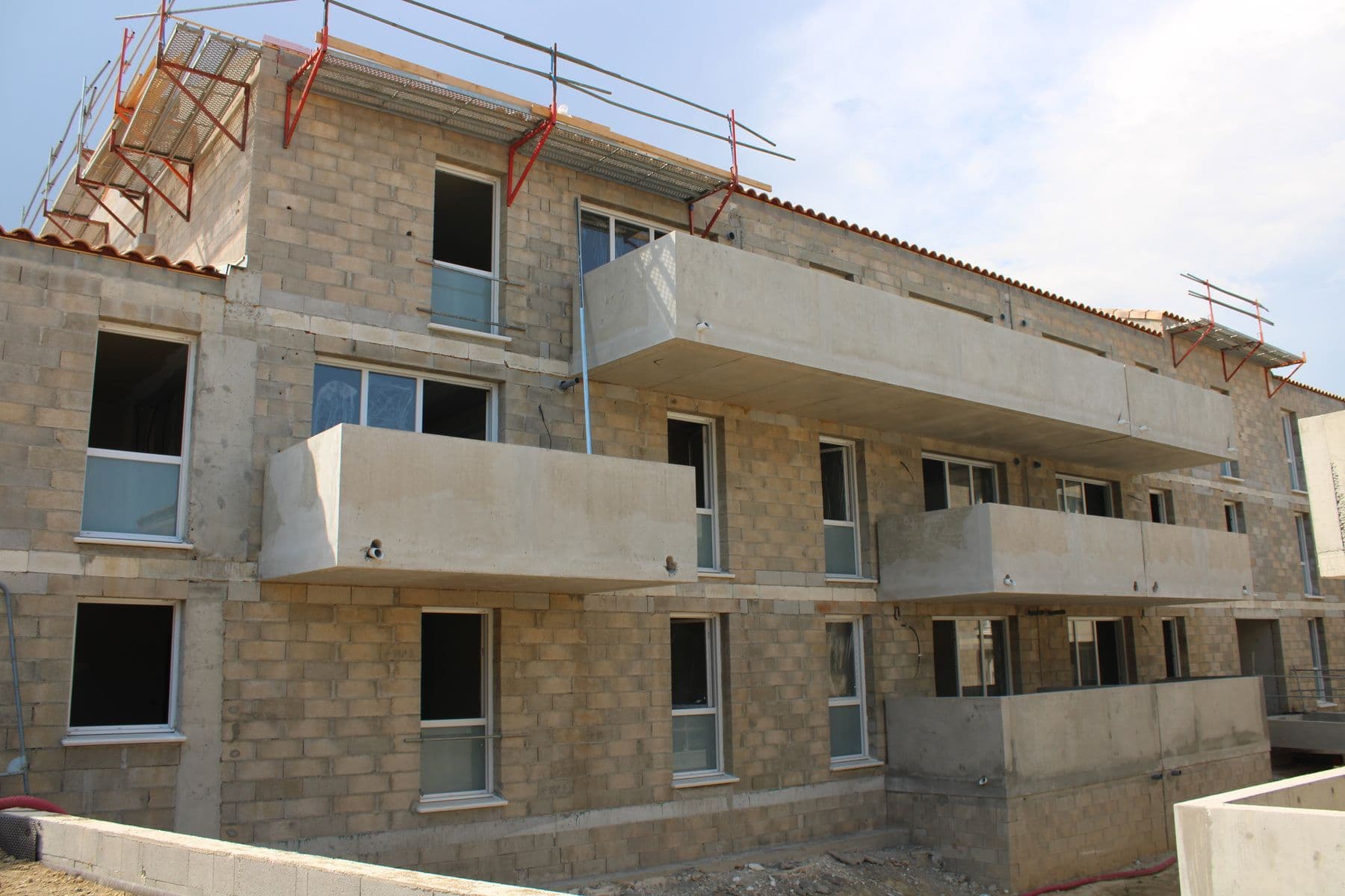 La Résidence Oppidum en construction : murs en blocs béton, balcons coulés et garde-corps de sécurité en rive de toiture